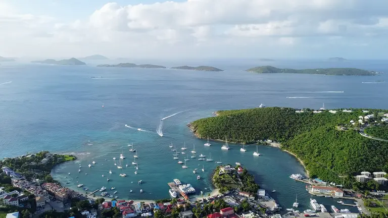 Aerial view of a bay full of sailboats, with islands beyond