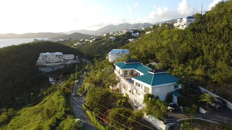 Aerial view of villas on a green hillside above the sea