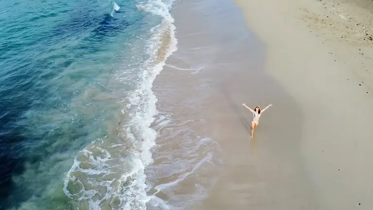 Aerial view of waves washing onto a white sand beach